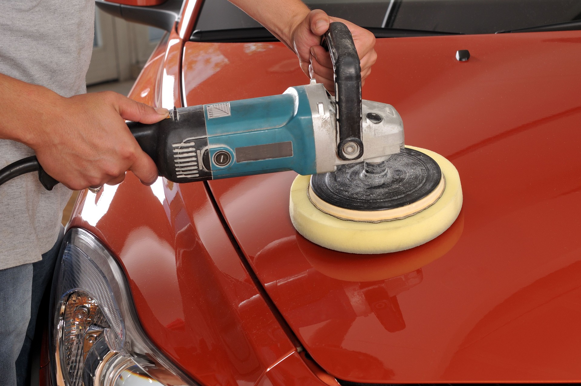 A red car being polished by a man